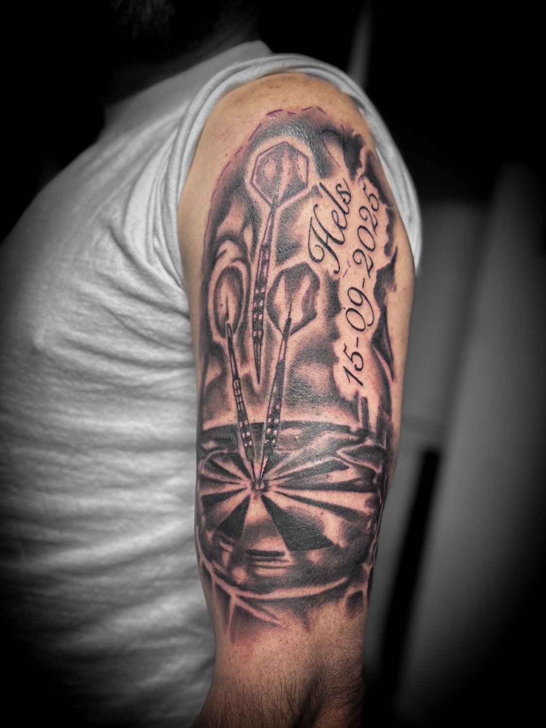 Tattoo of a bicycle chainring, chain, and gears on a person's upper arm, with a date and word inscribed.