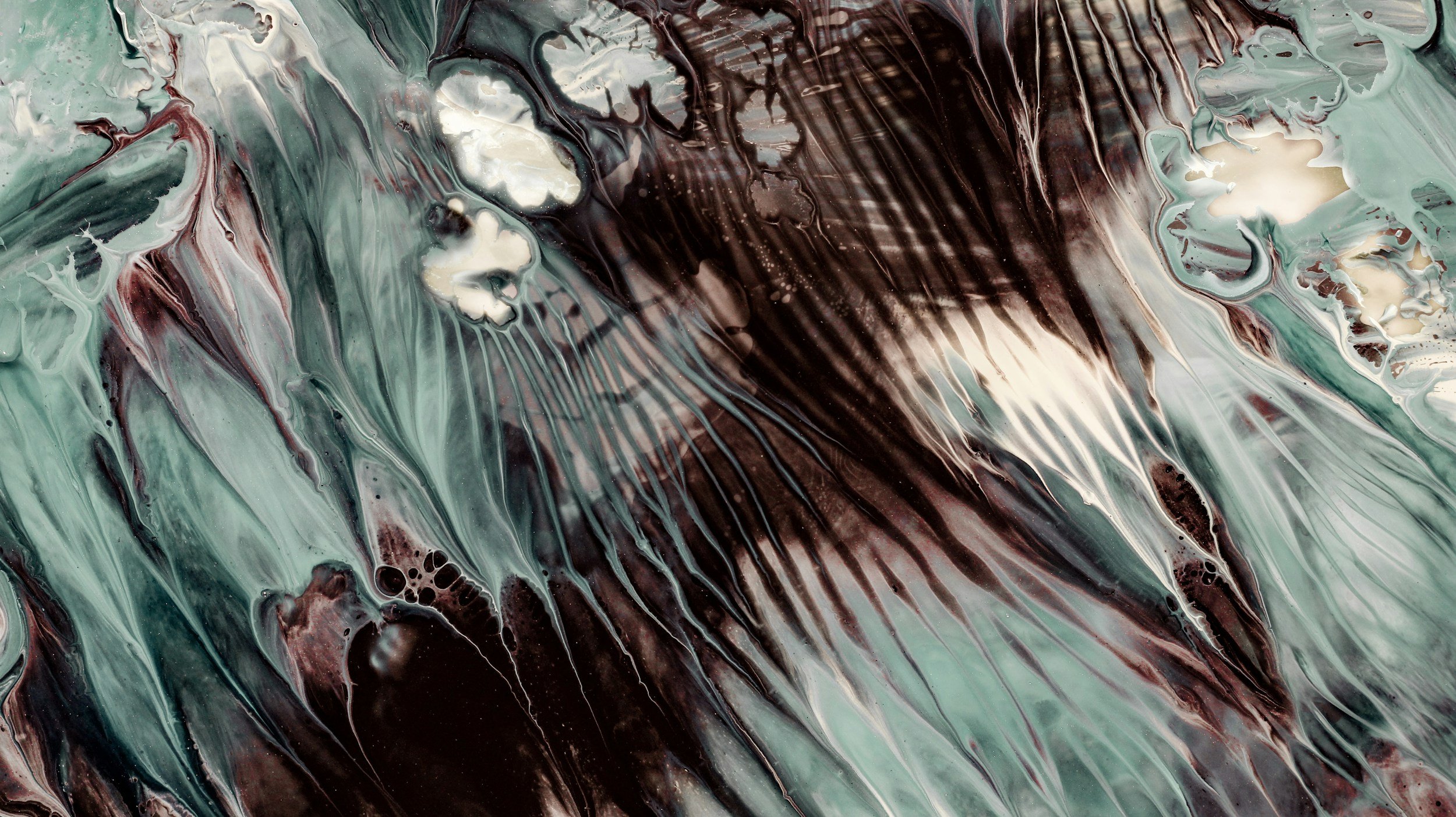 Abstract swirling paint with shades of green, black, cream, and hints of red and white.