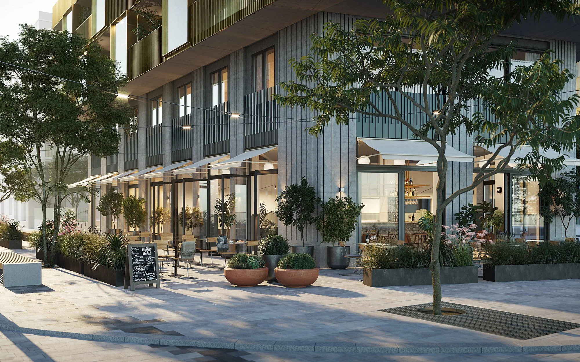 Uteservering utomhus med bord och stolar, omringad av träd och växter, i ett modernt bostadsområde.