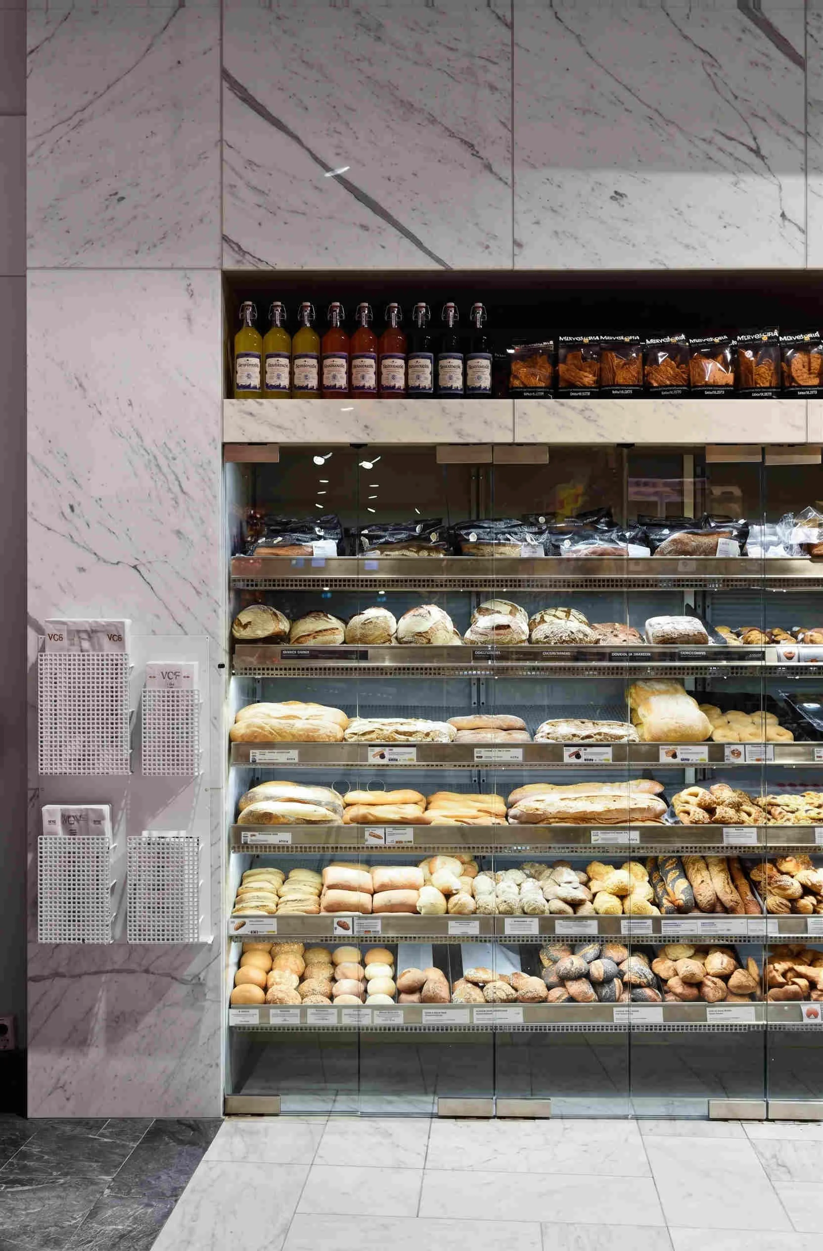 Bild av ett bageriskåp fyllt med olika sorters bröd och bakverk, samt drycker på hyllan i projektet Ica Esplanad i Stockholm
