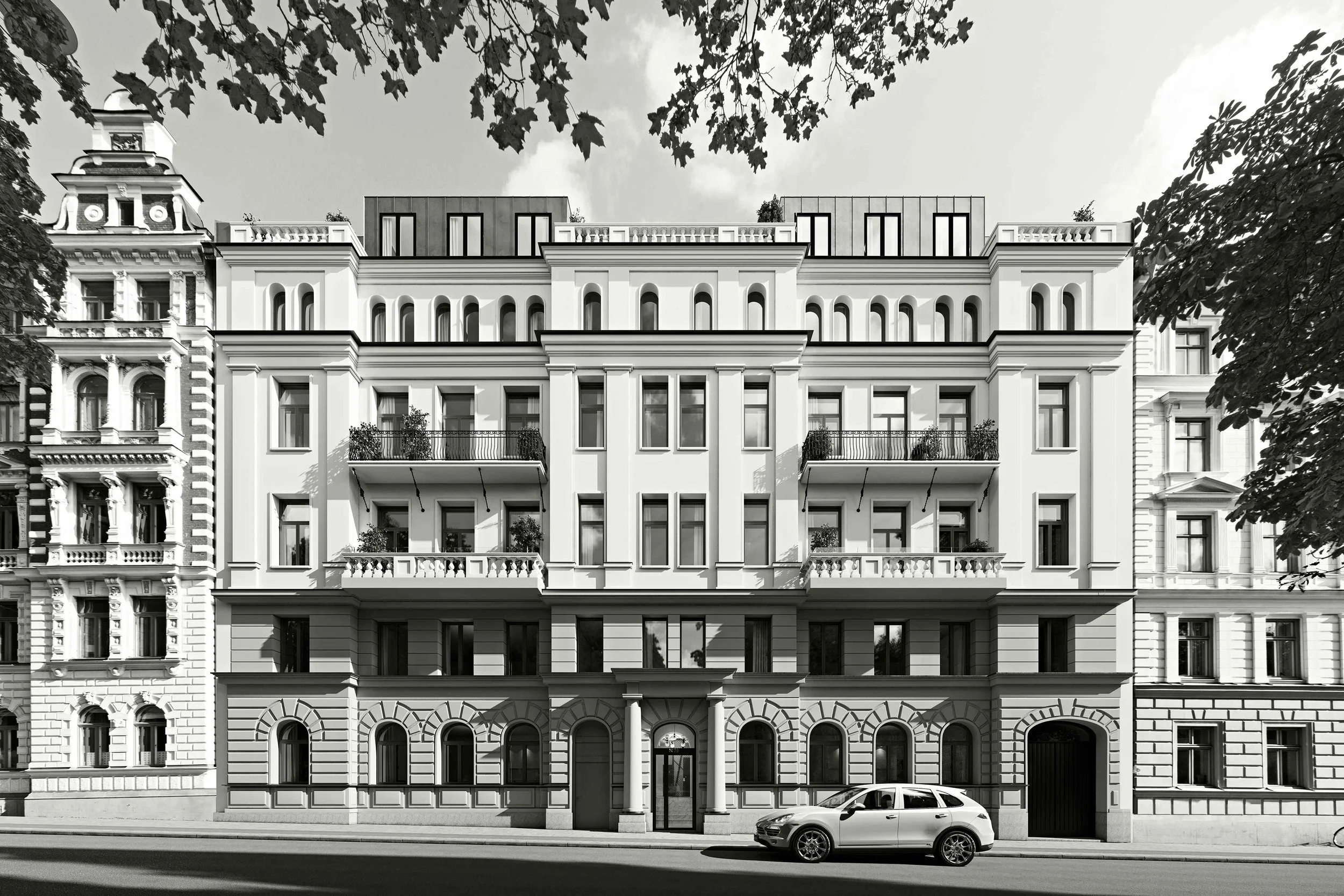 Svartvitt foto av en stadsvåning med modern arkitektur, terrasser med räcken, och bilar parkerade framför byggnaden, omgiven av träd.