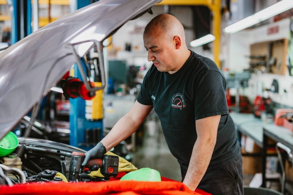 A mechanic working on a car engine in a garage workshop.