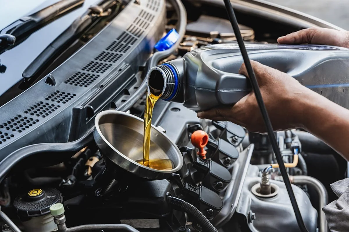 Person pouring motor oil into a car engine.