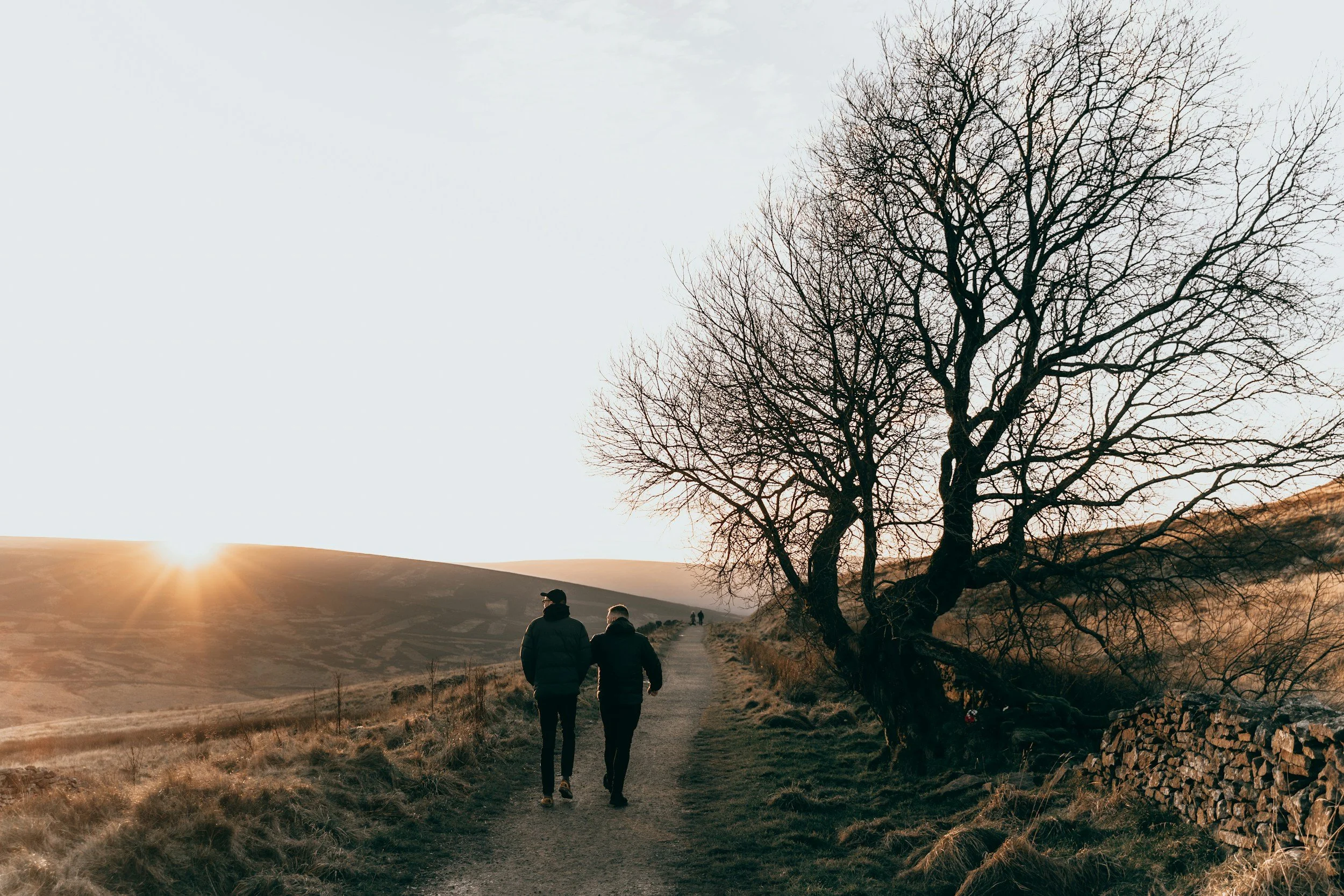 Deux personnes marchent sur un sentier en pleine nature au coucher du soleil, illustrant l'accompagnement et le cheminement proposés en coaching par Reliences.