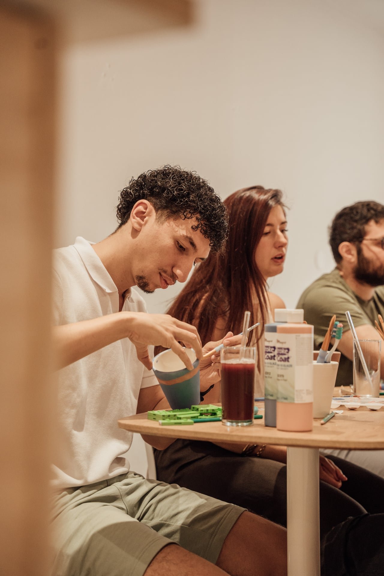 Groupe de personnes assises à une table, participant à une activité de groupe, avec des aliments et des boissons sur la table.