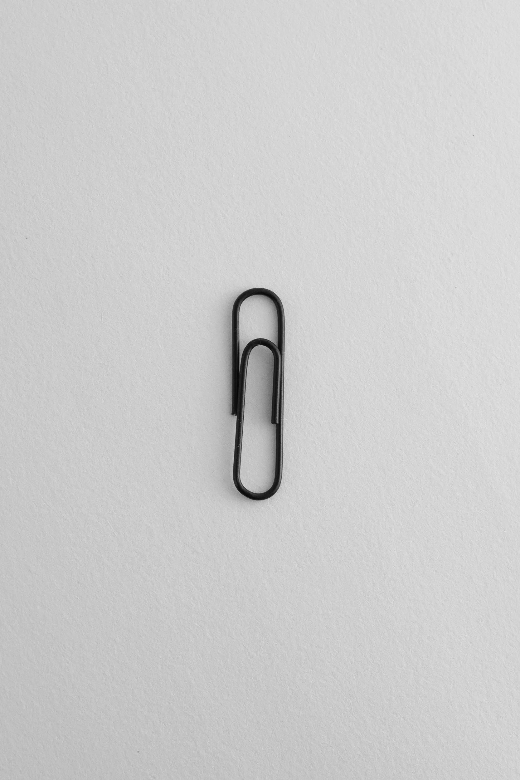 A black paperclip on a white textured background.