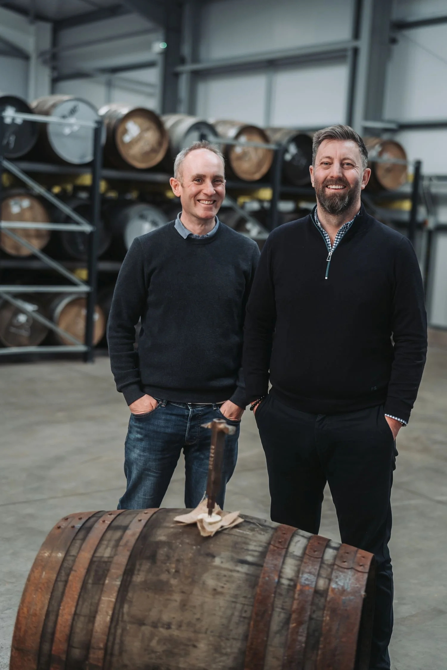 Two clients visiting the Auld Bond warehouse standing in front of cask