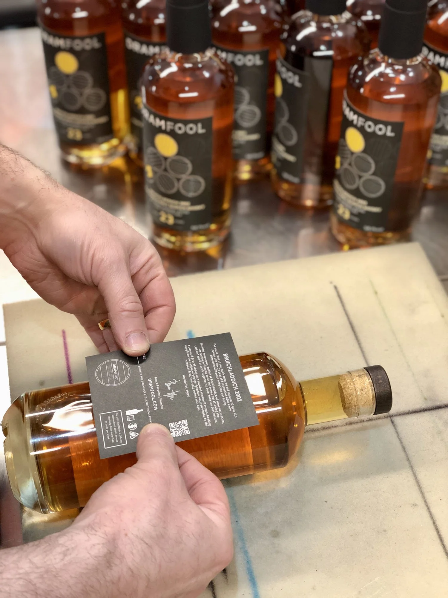 Label being applied to Scotch whisky bottle in the Auld Bond warehouse.