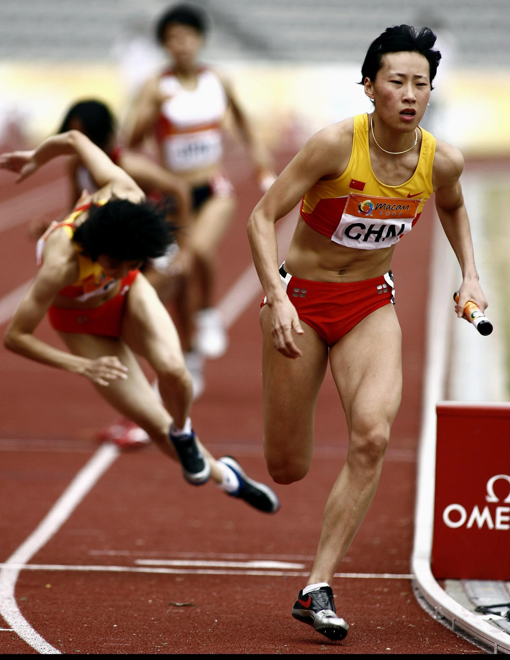 Huang Xiaoxiao (R) of China accelerates after being passed the baton by Tang Xiaoyin (L), who stumbled on the third baton change, during the women's 4x400m relay final at the 4th East Asian Games in Macau, 04 November 2005.