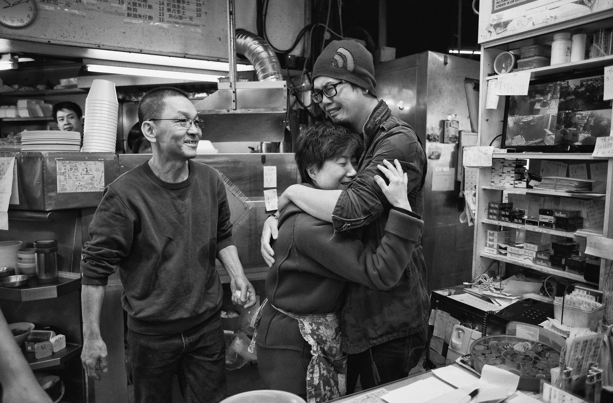Longtime customer Chan Lok (R) cries as he hugs the owner Chan Man-ying (centre), as her husband and owner Chow Cheug-tei (L) looks on at Hap Wah food stall, some 9 minutes before its official closure, at Fu Shin Estate, Tai Po.  Hap Wah will close a
