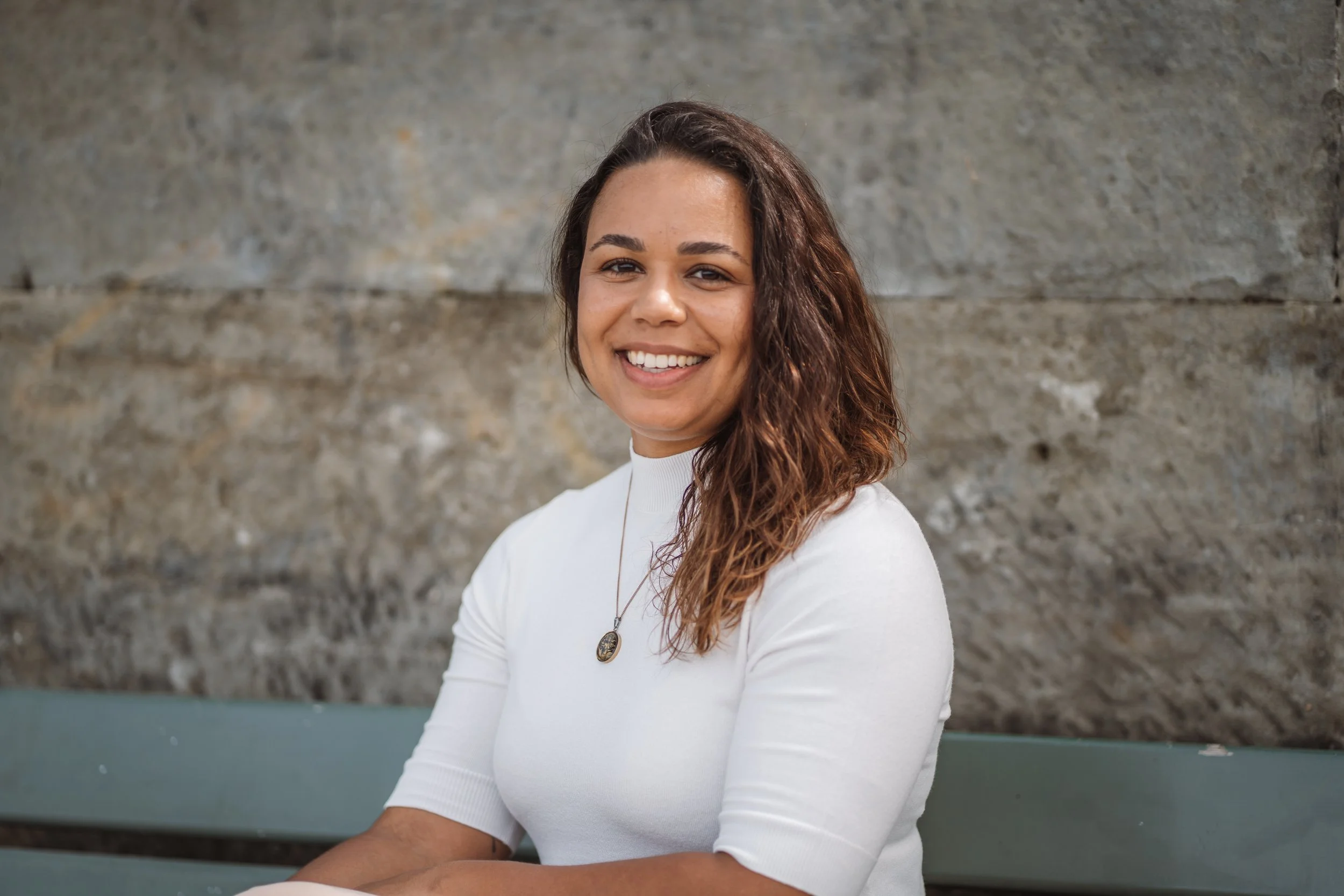 Nyara Kaiser-Sutter, Arbeits- und Organisationspsychologin MSc, sitzend an einer Mauer in Bern.