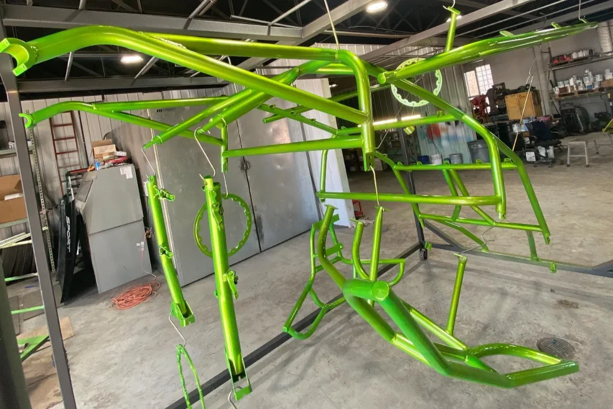 Bright green metal bicycle frame hanging in a workshop.