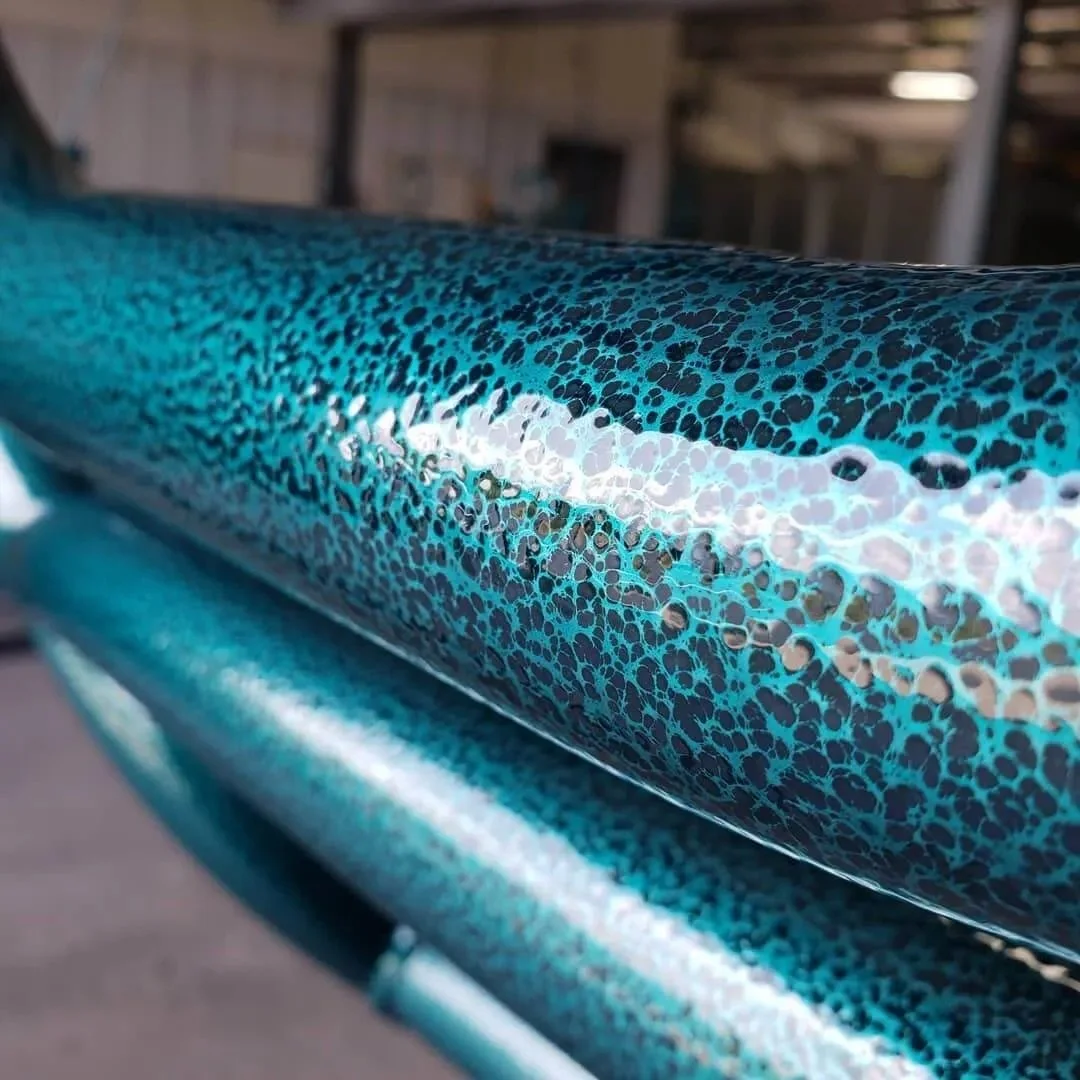 Close-up of a blue and black speckled bicycle frame with a shiny, reflective coating.