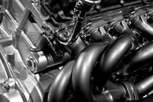 Close-up of a motorcycle engine with black exhaust pipes and metallic engine parts.