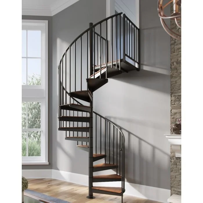 A modern black metal spiral staircase inside a home with light wood steps, a curved handrail, and vertical bars for support. The staircase is situated near a large window and a stone fireplace.