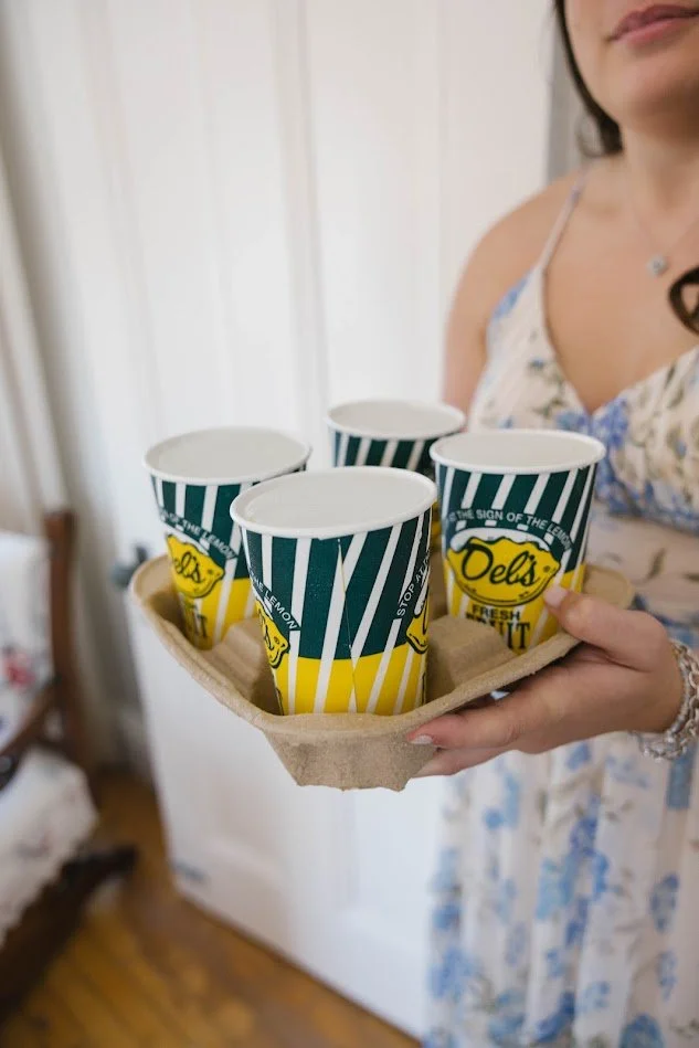 A woman holding a tray with five cups of Del's frozen lemonade.