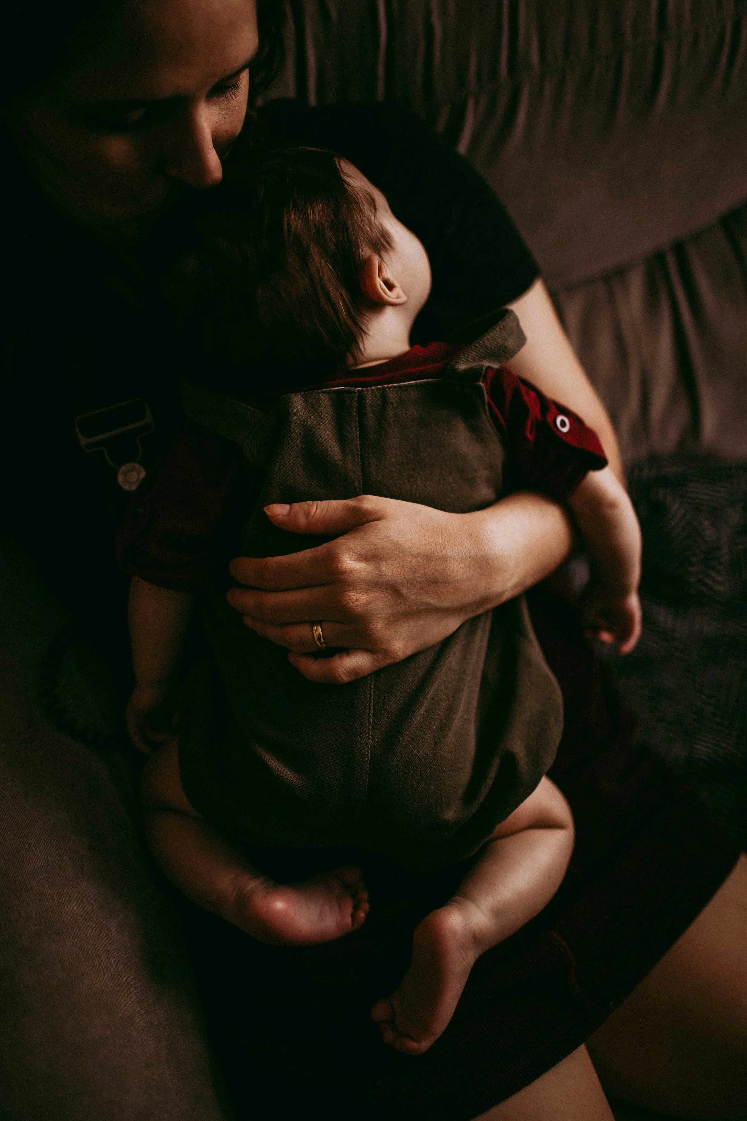 Une personne adulte tenant un enfant petit contre elle, dans une atmosphère intime et chaleureuse.