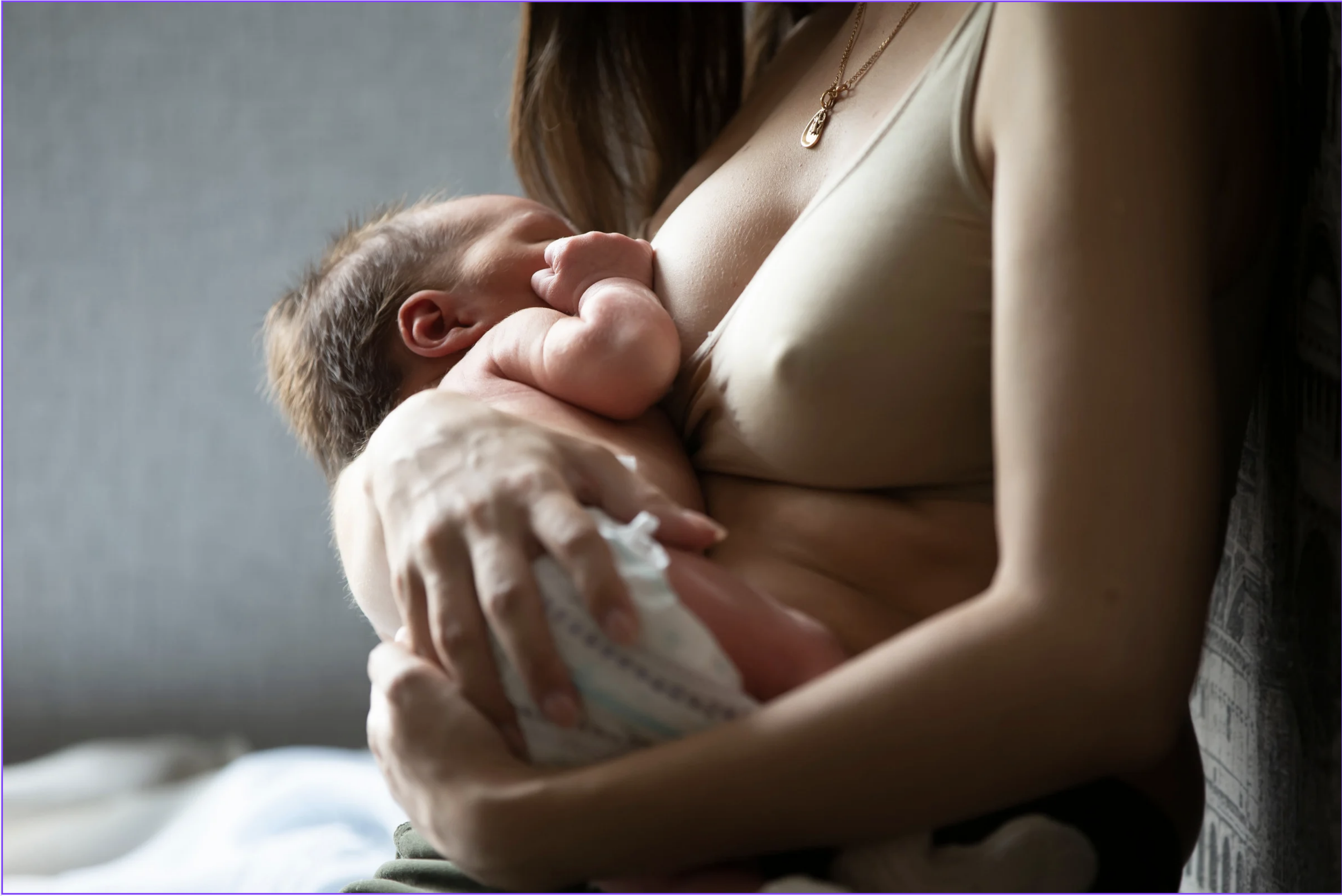 Une mère allaite son bébé dans une pièce à lumière douce.