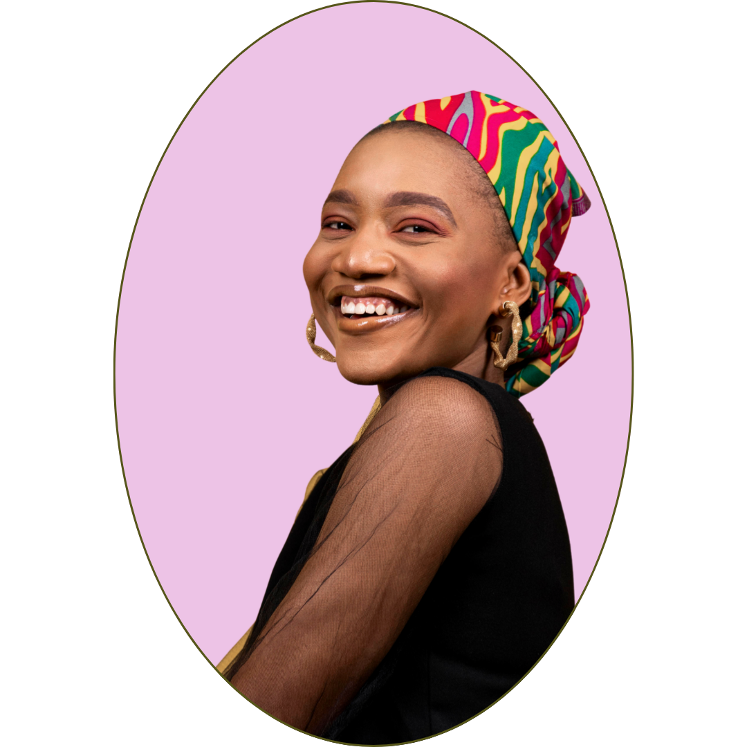 Portrait of a smiling woman wearing a colorful headscarf, black top with sheer sleeves, and large gold earrings, against a purple background.