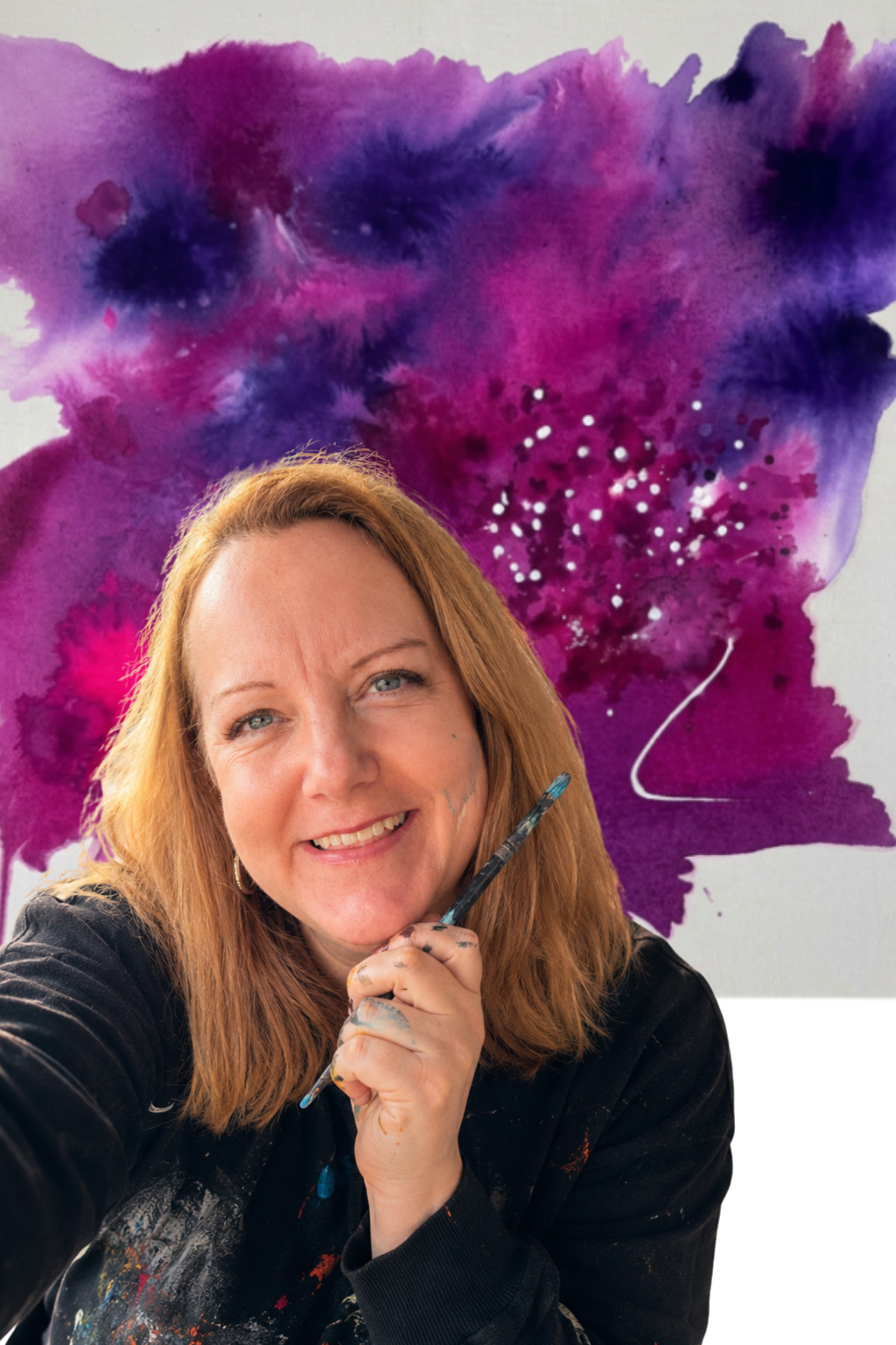 A woman with red hair smiling and holding a paintbrush, with a colorful abstract watercolor background featuring shades of purple and pink.