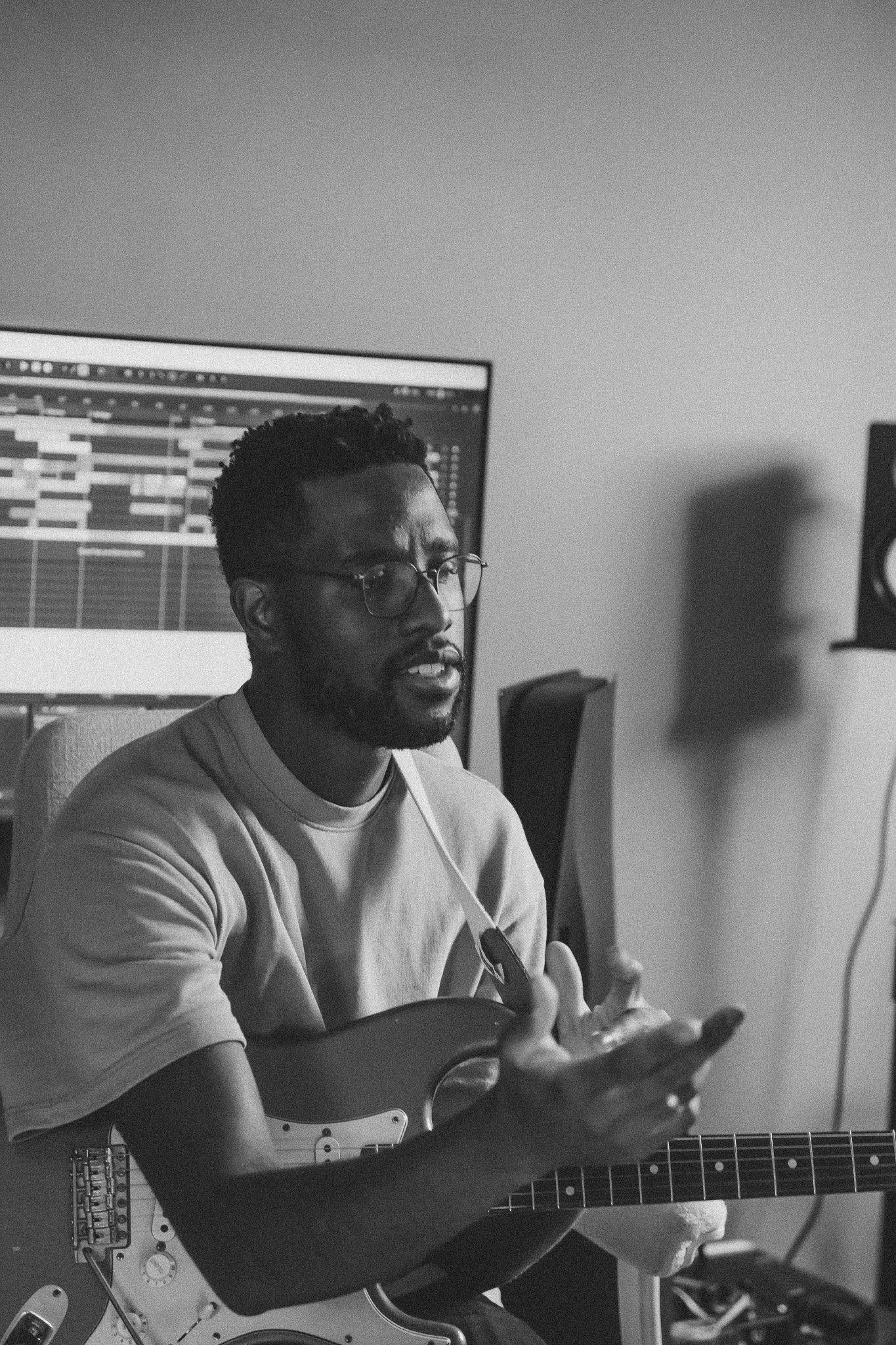 Anthony Trustfull met een gitaar in studio, muziekles aan het geven.