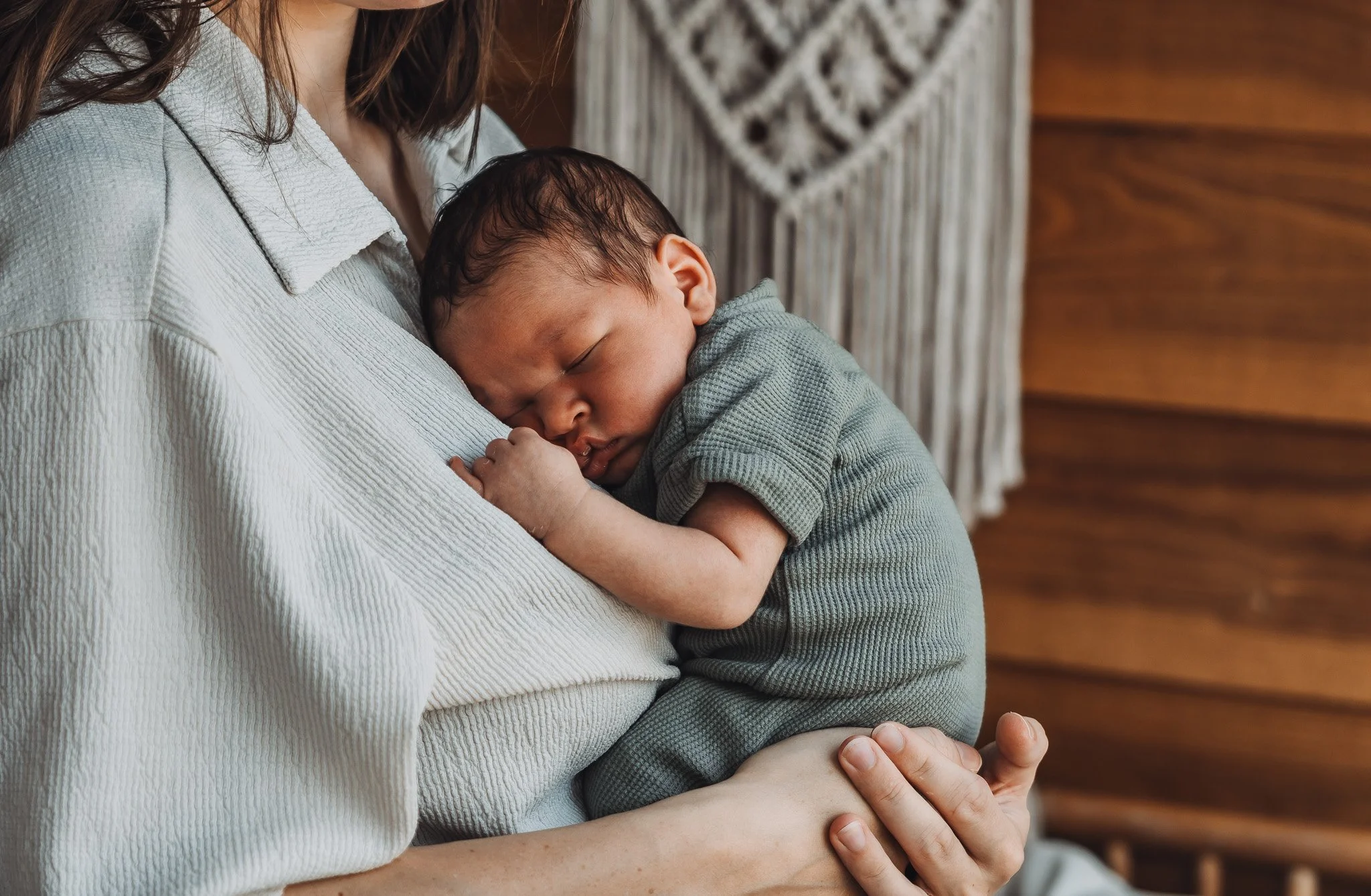 Een persoon houdt een slapende baby vast op schoot terwijl ze in een binnenruimte zitten.