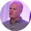 Bald man with a checkered shirt speaking in a TV studio or interview setting