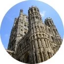 Close-up of the Gothic-style, stone cathedral with tall towers against a blue sky.