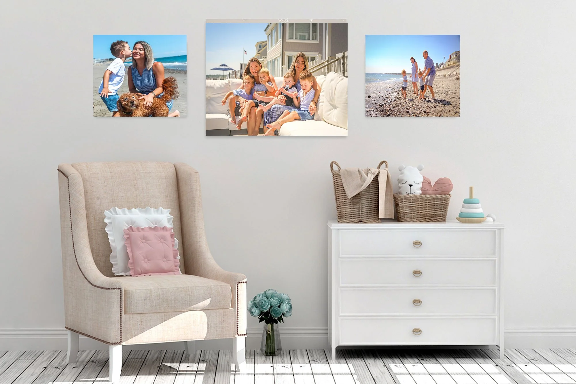 Living room wall decorated with three beach-themed photos, beige armchair with pink pillow and white trim, white dresser with woven basket, plush bear, turquoise flowers, and children's stacking toy.
