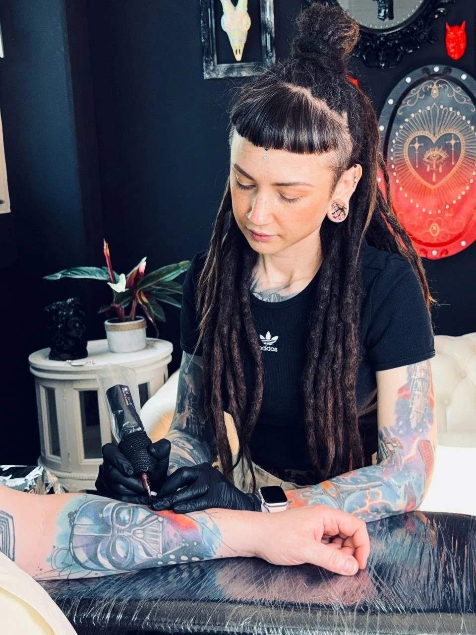 Tattoo artist Maya Marina working with a tattoo machine in the studio.