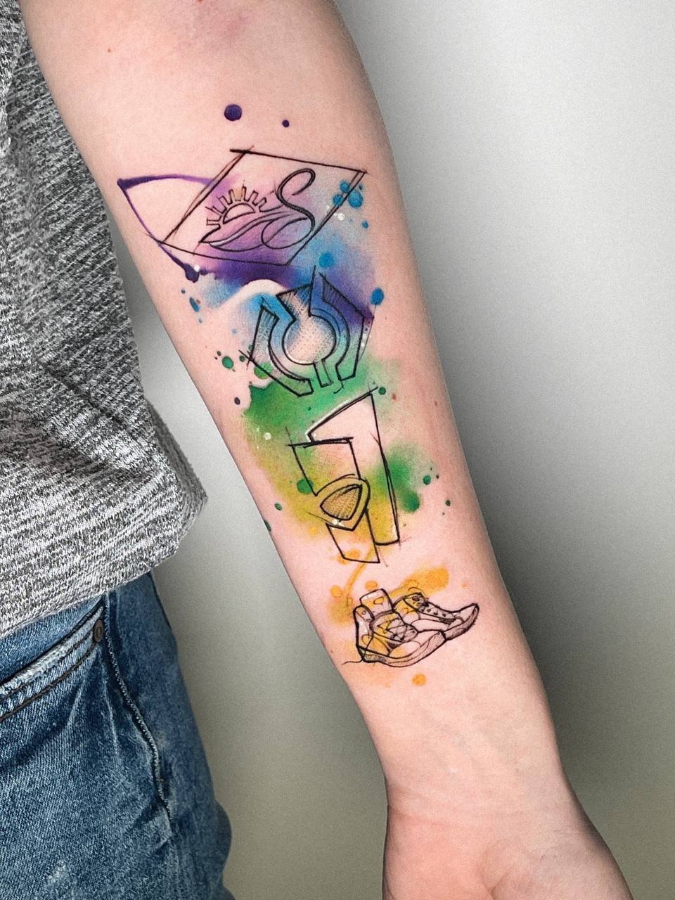 Farbiges Sketch-Style-Tattoo mit Wanderschuhen, Symbolen und aquarelliertem Hintergrund