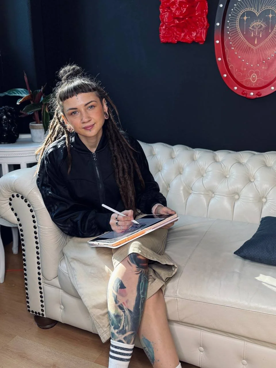 Maya Marina working on a tattoo design with a tablet in a tattoo studio.