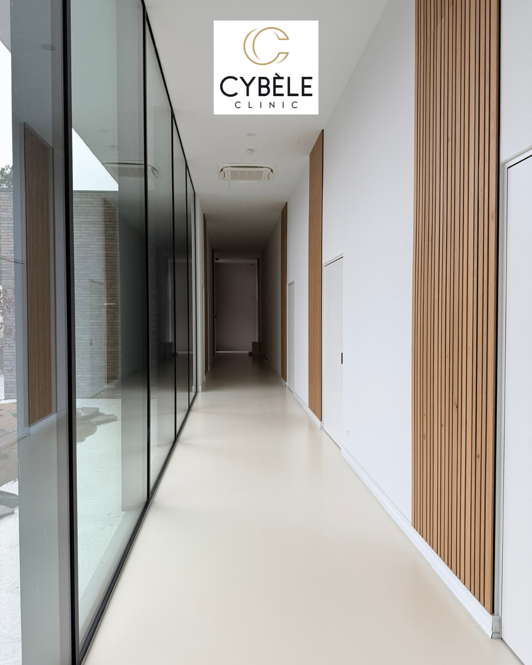 Couloir moderne d'une clinique avec mur en bois clair et grandes fenêtres en verre