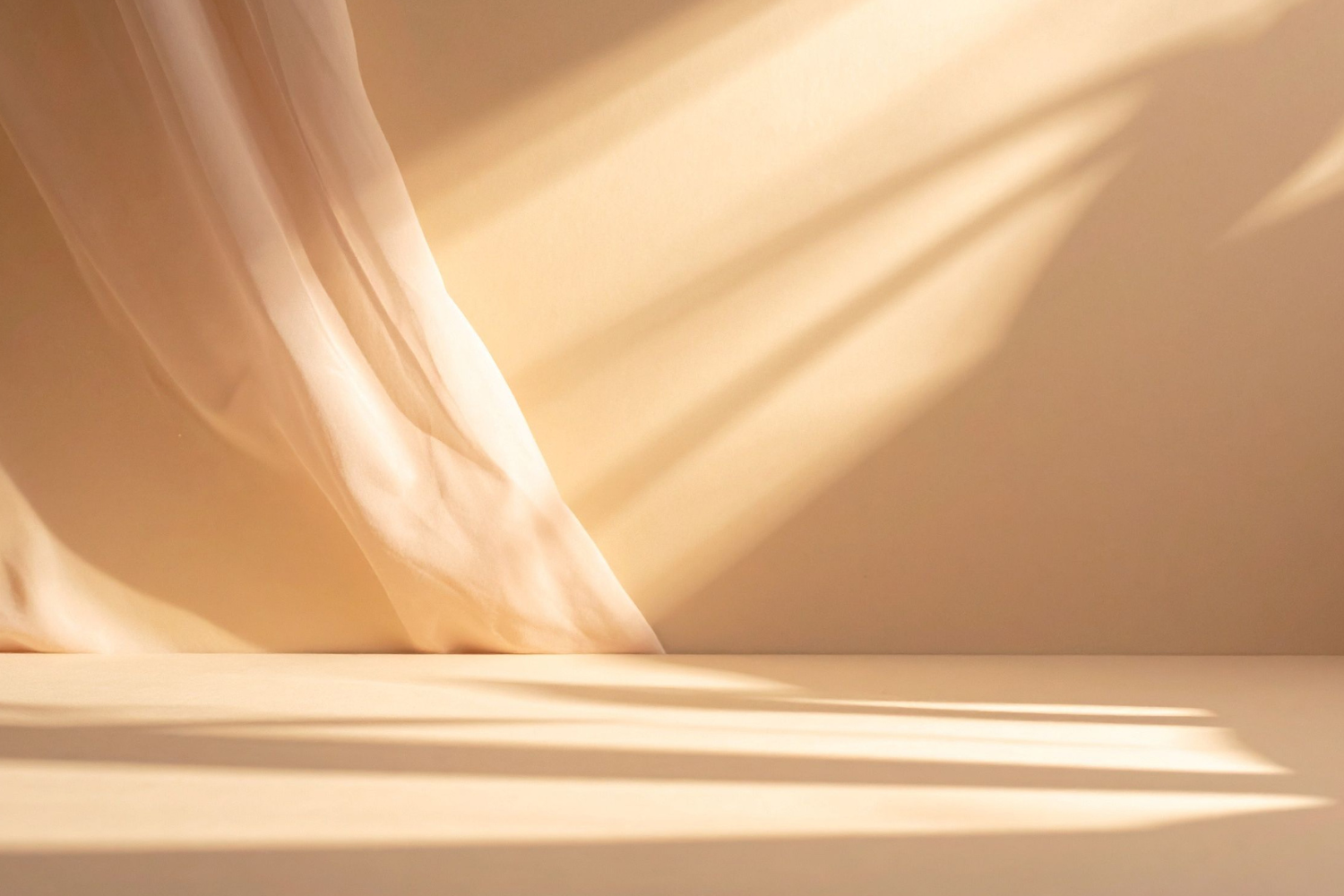 Light-colored curtains with shadows cast on a wall and surface in a room.