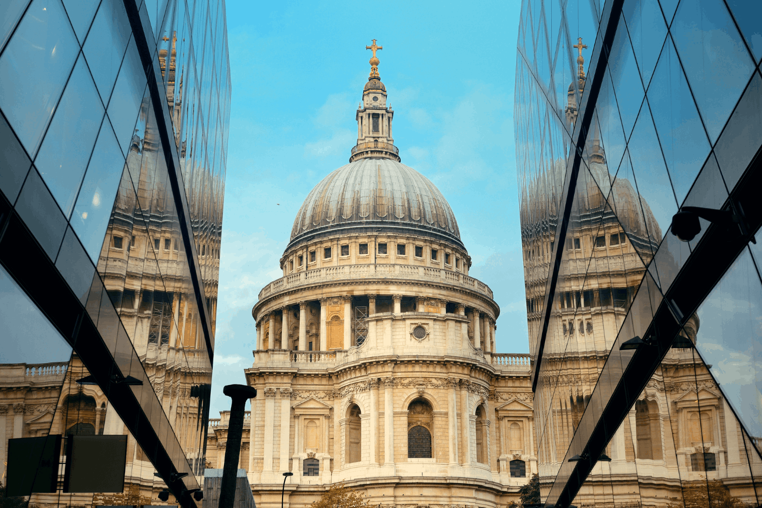 St. Paul’s Cathedral viewed through modern glass buildings, with reflections of the cathedral on the glass surfaces.