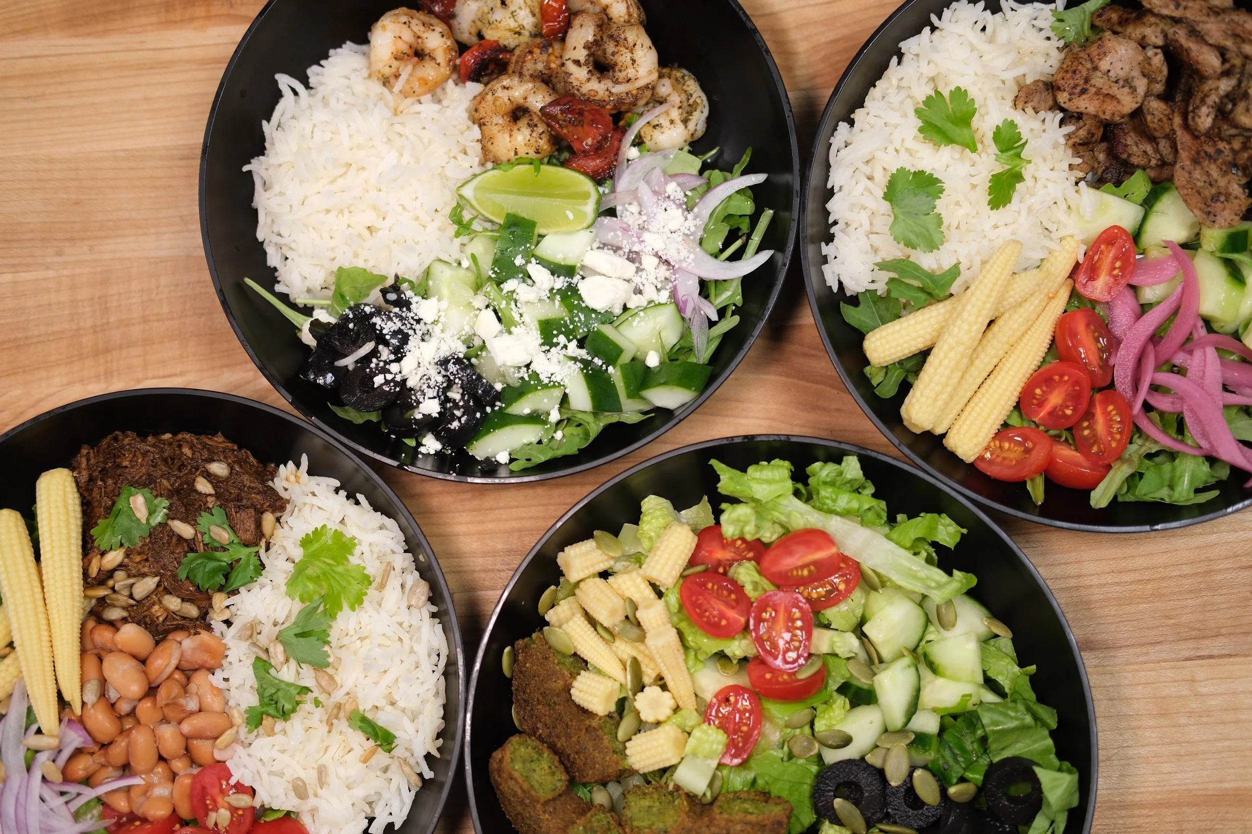 Pita & Maíz bowls with rice, fresh vegetables and grilled proteins.