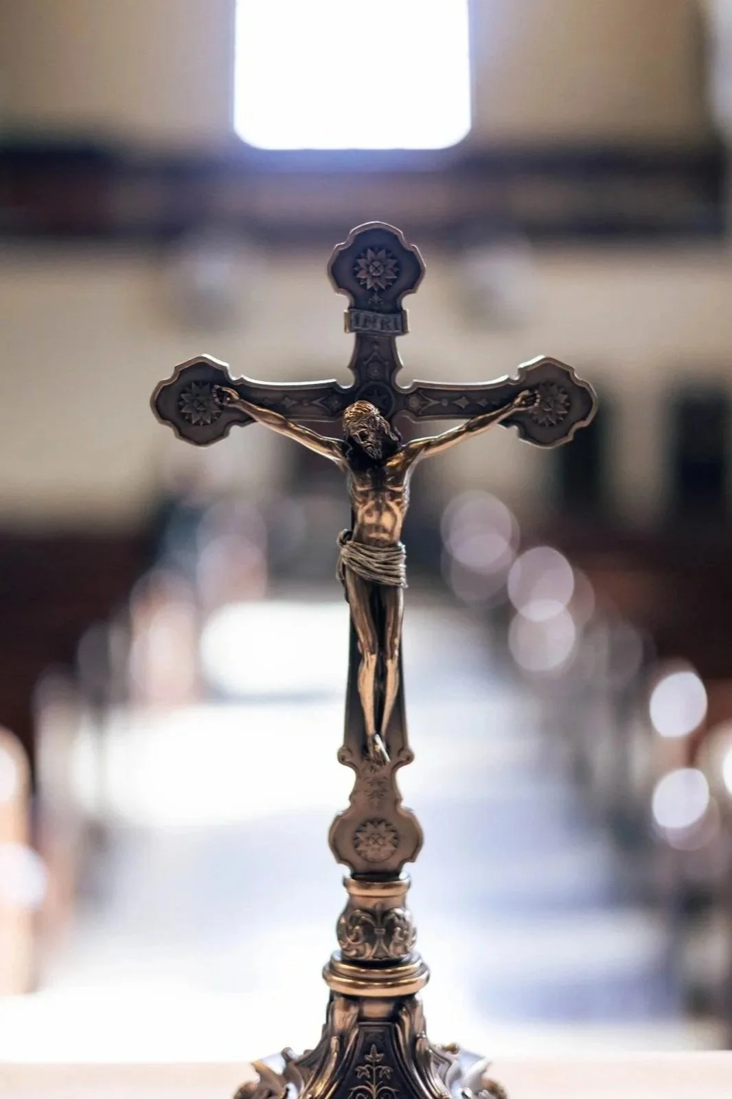Religious crucifix sculpture of Jesus on the cross, with a blurred background.