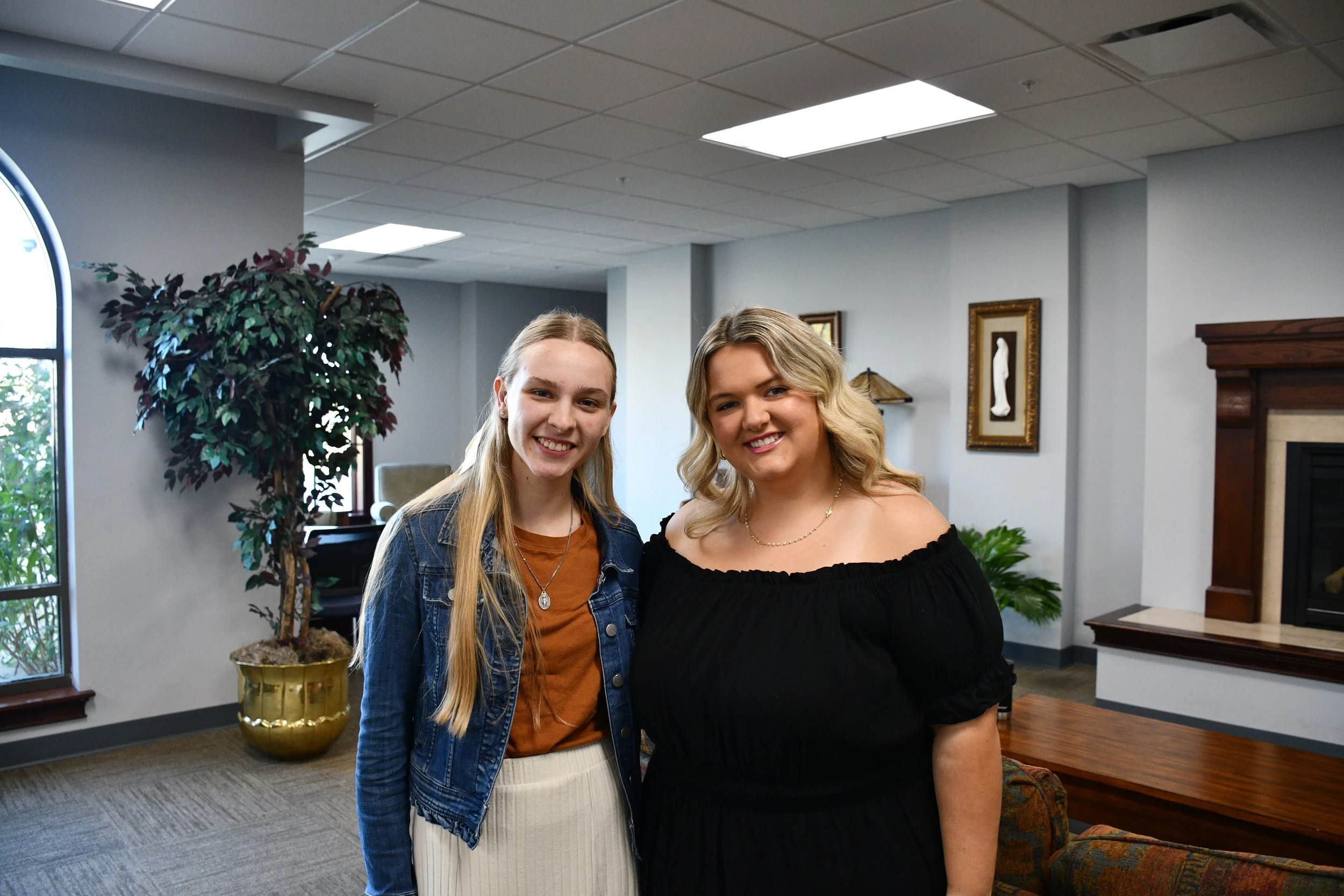 Two young women are standing together in St. John Paul II Newman Center Lobby.