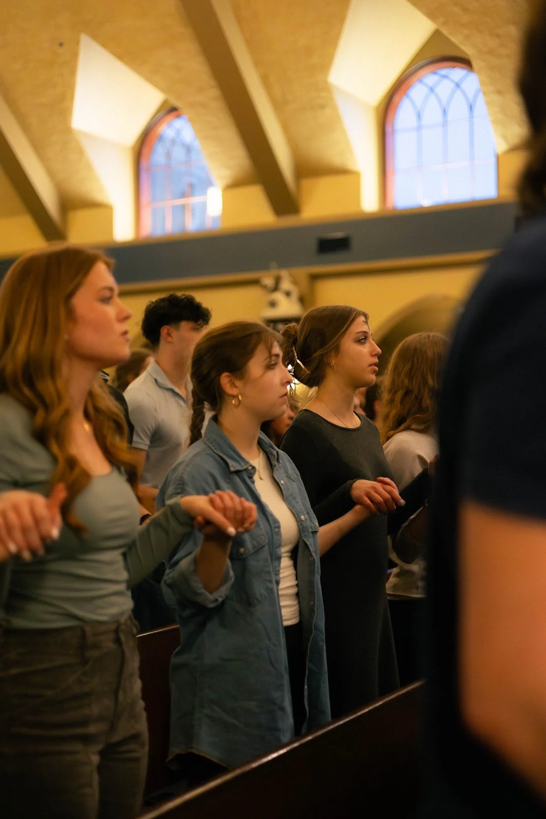 People standing inside a church, holding hands and praying.