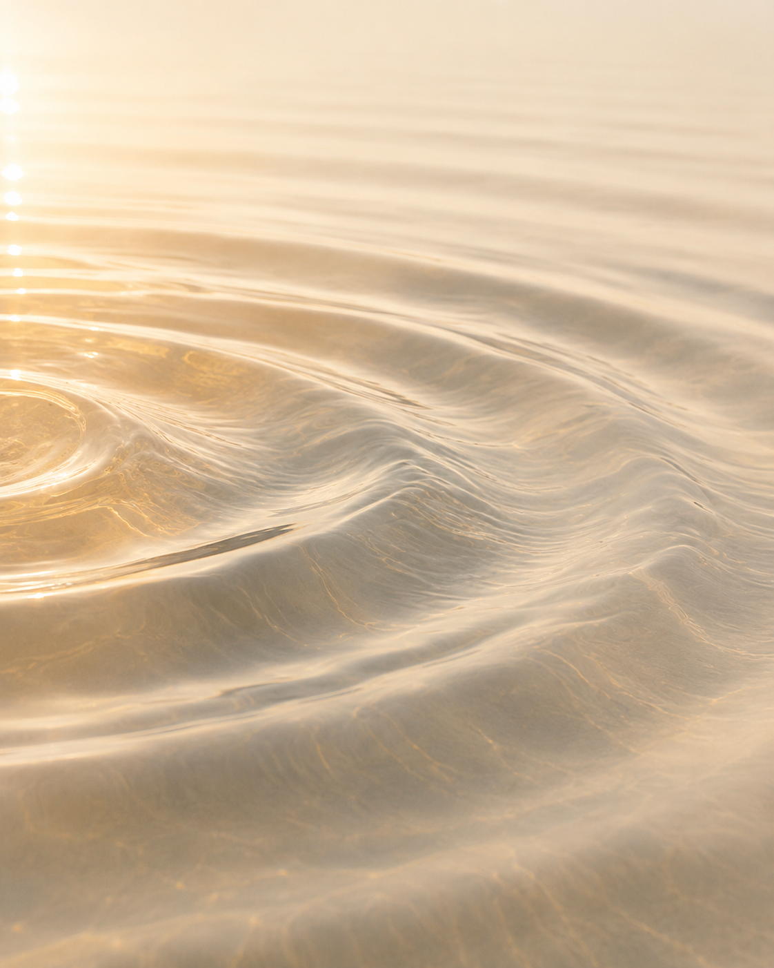 Close-up of calm, gentle water ripples with golden sunlight reflections.