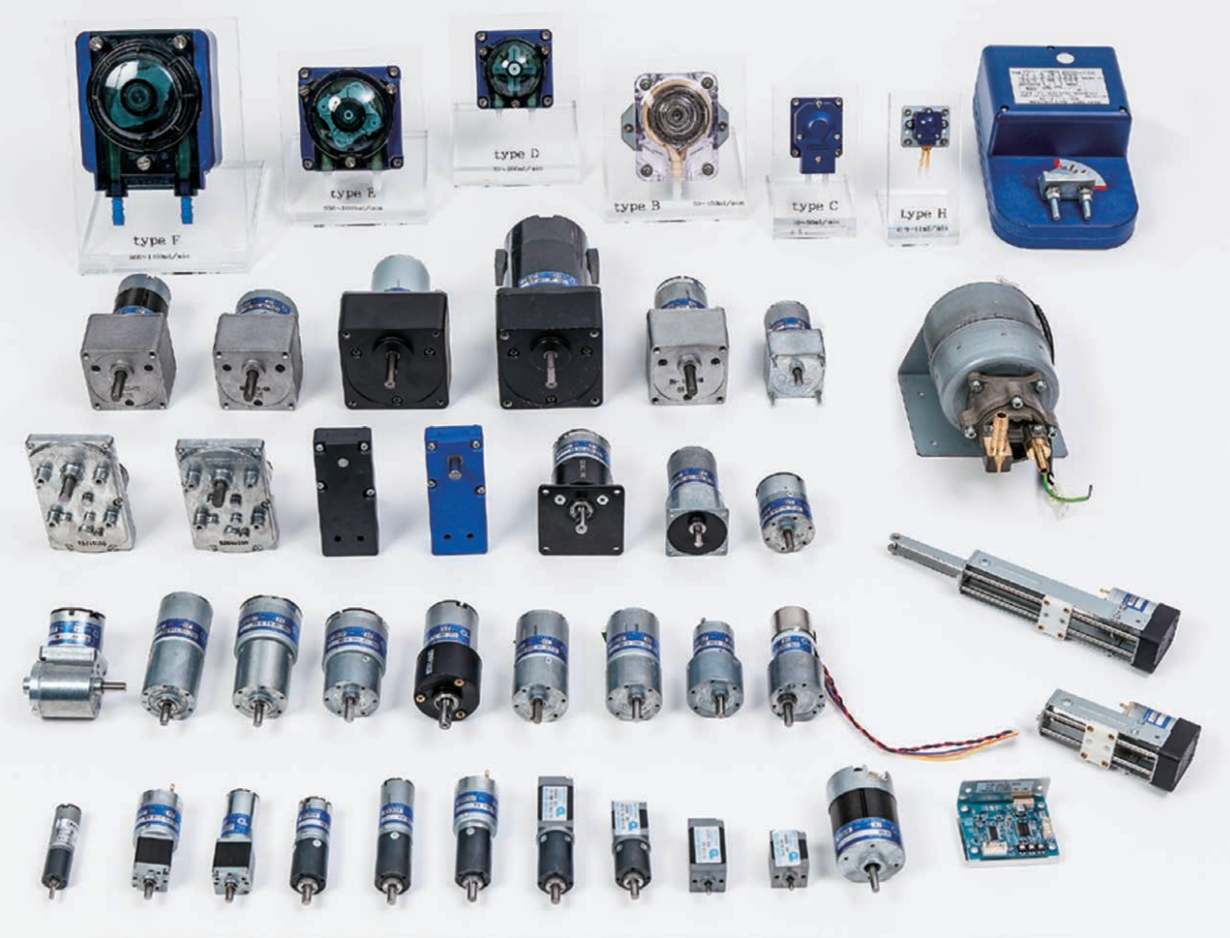 Collection of various small motors, actuators, and electronic components arranged on a white surface, including labeled types.