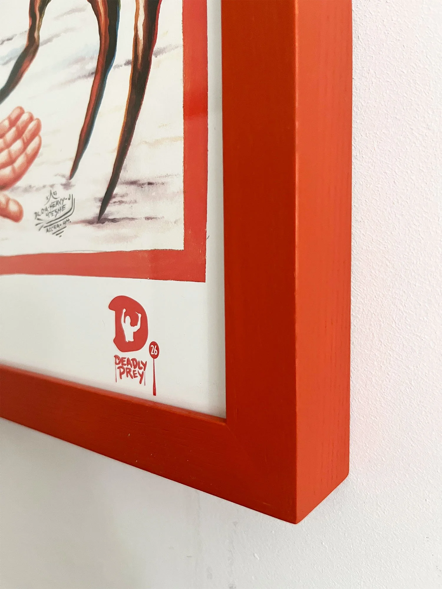 Close-up of a orange framed poster on a white wall showing a comic-style illustration of the feature film, "the Thing", with the 'Deadly Prey' logo.
