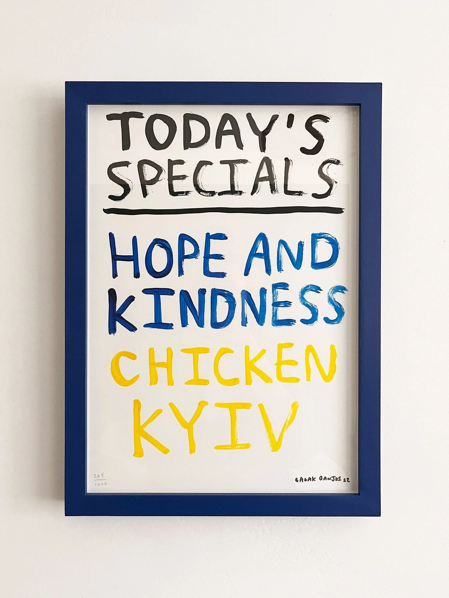 Whiteboard with handwritten text and a blue frame. The text reads: "Today's Specials" in black, "Hope and Kindness" in blue, and "Chicken Kentucky" in yellow, with some smaller writing at the bottom.