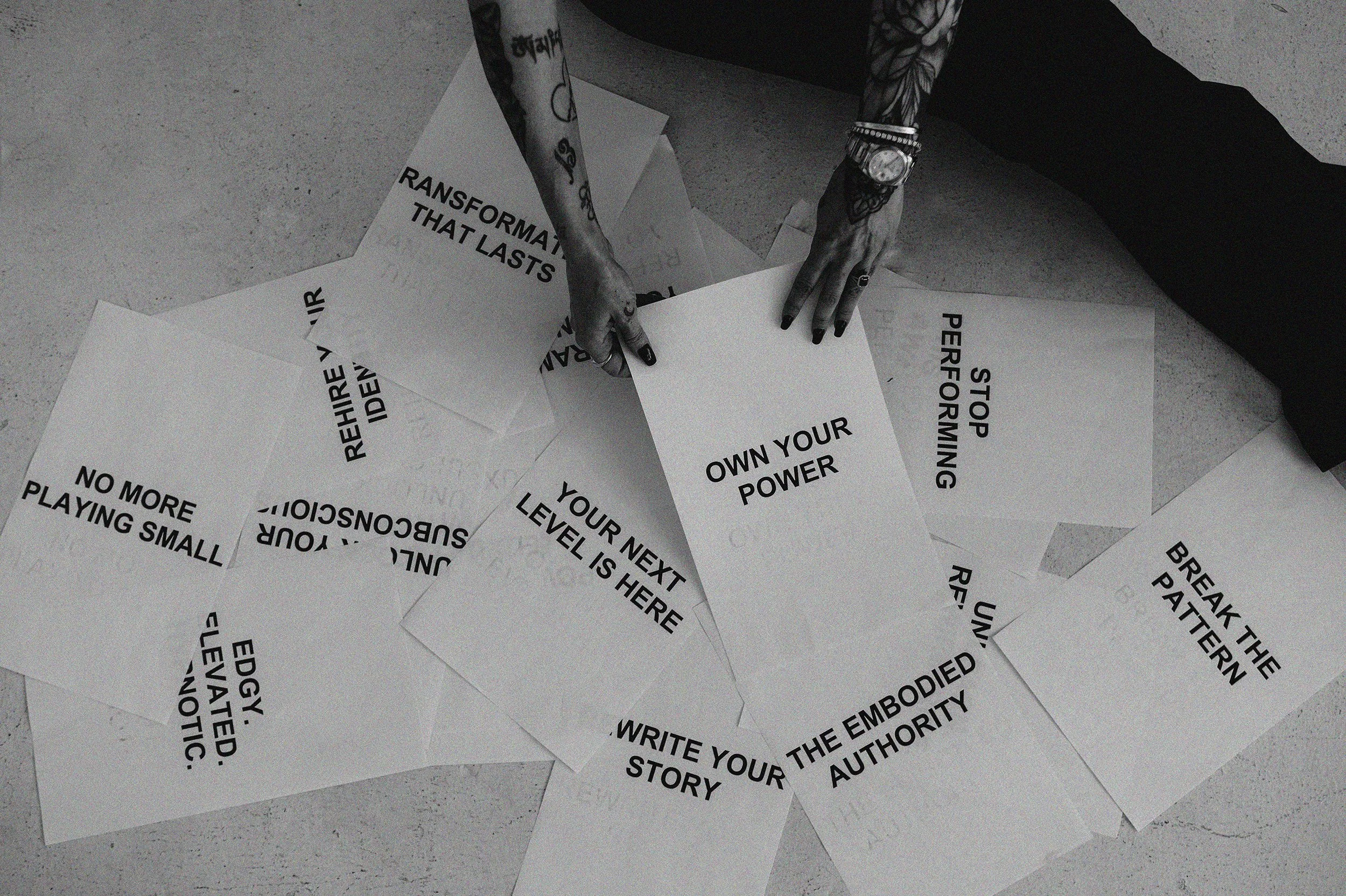 Hands holding papers that read "Own your power", "Your next level is here" and "The embodied authority"