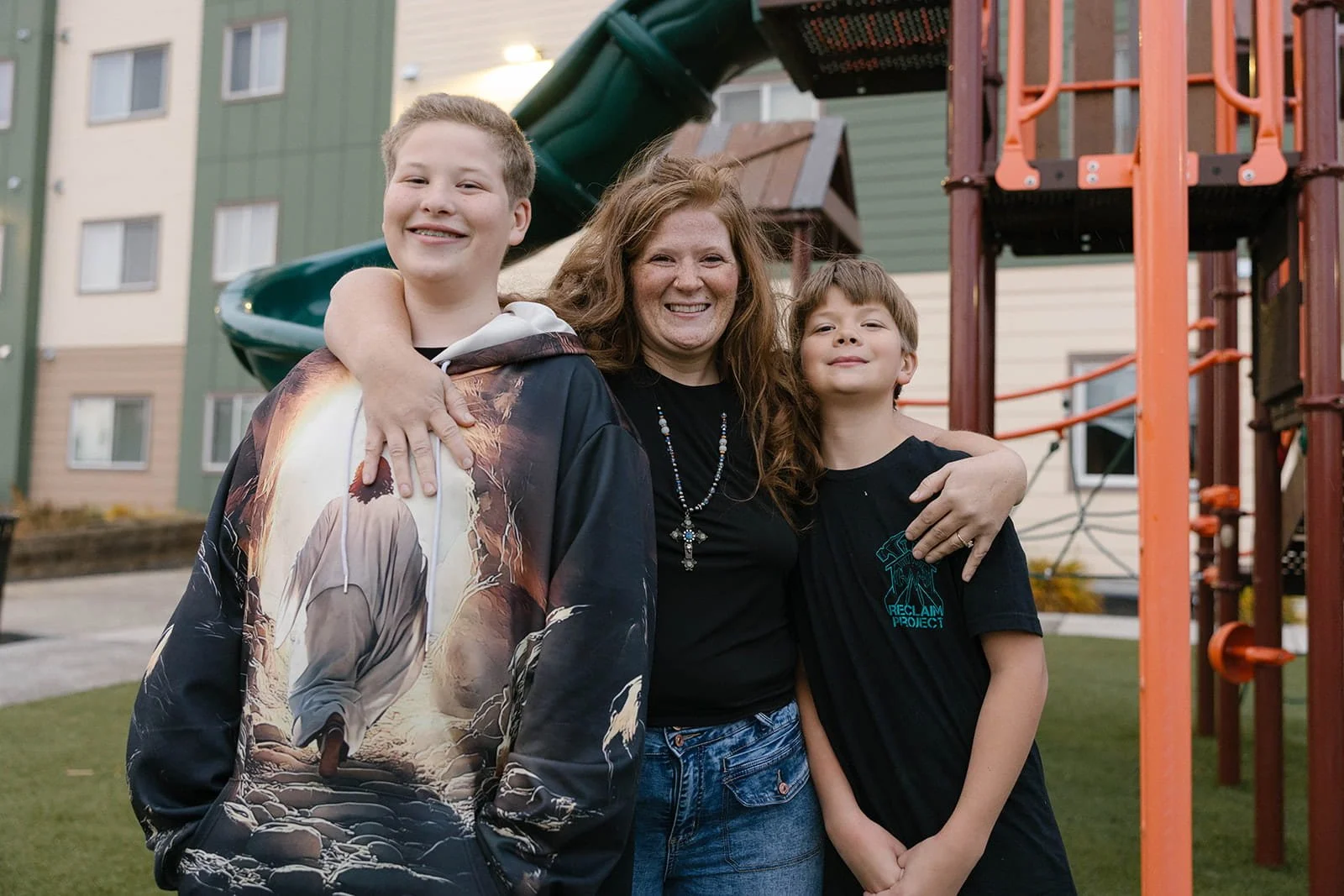 Resident of a Community Frameworks property, Ivory, and her two sons outside of the Sinto Commons.