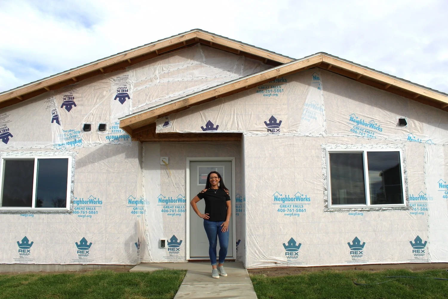 Woman standing in front of a new home under construction in Spokane, WA.