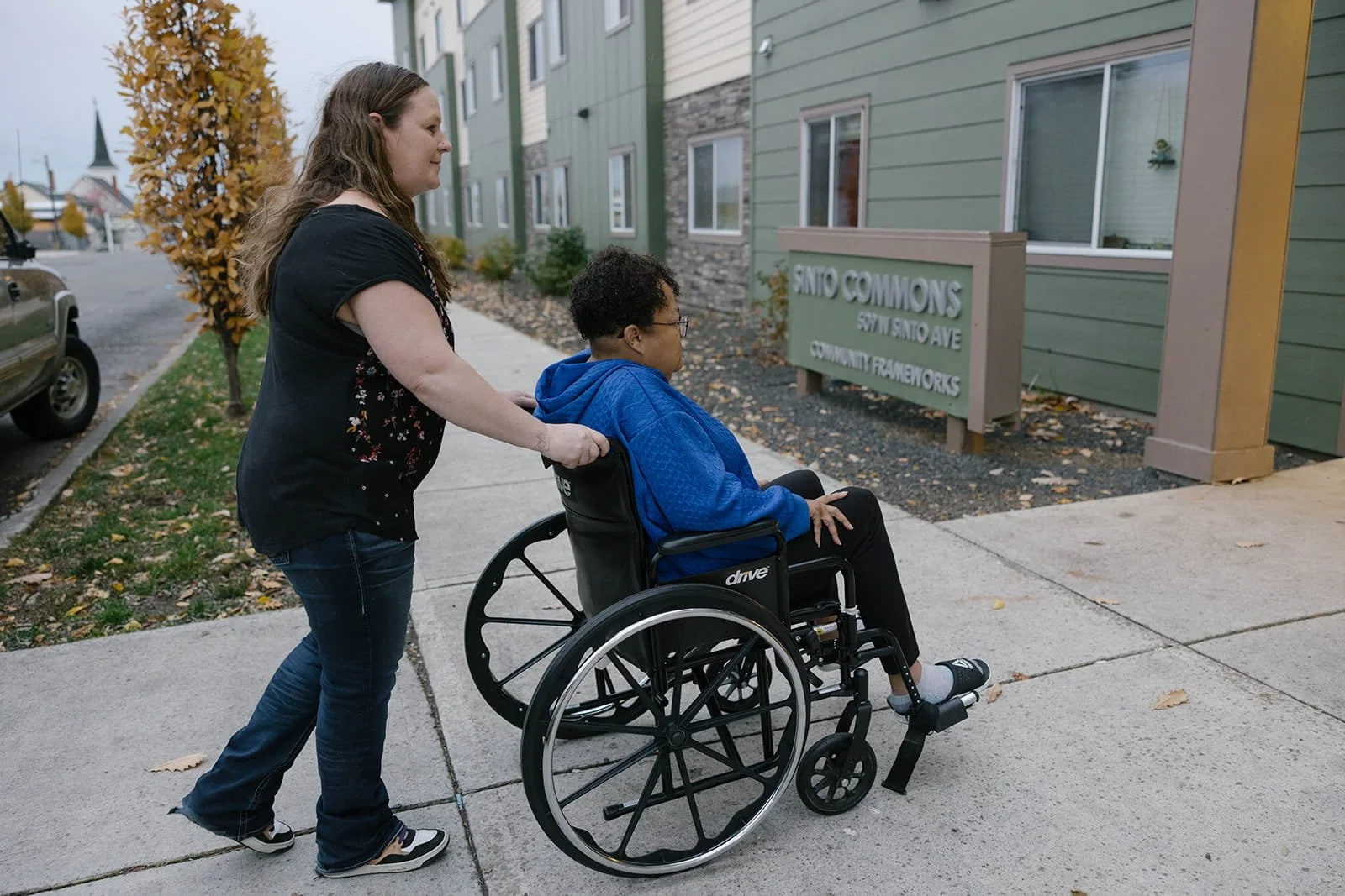 Woman pushing another woman in a wheelchair into Sinto Commons apartments in Spokane, WA.