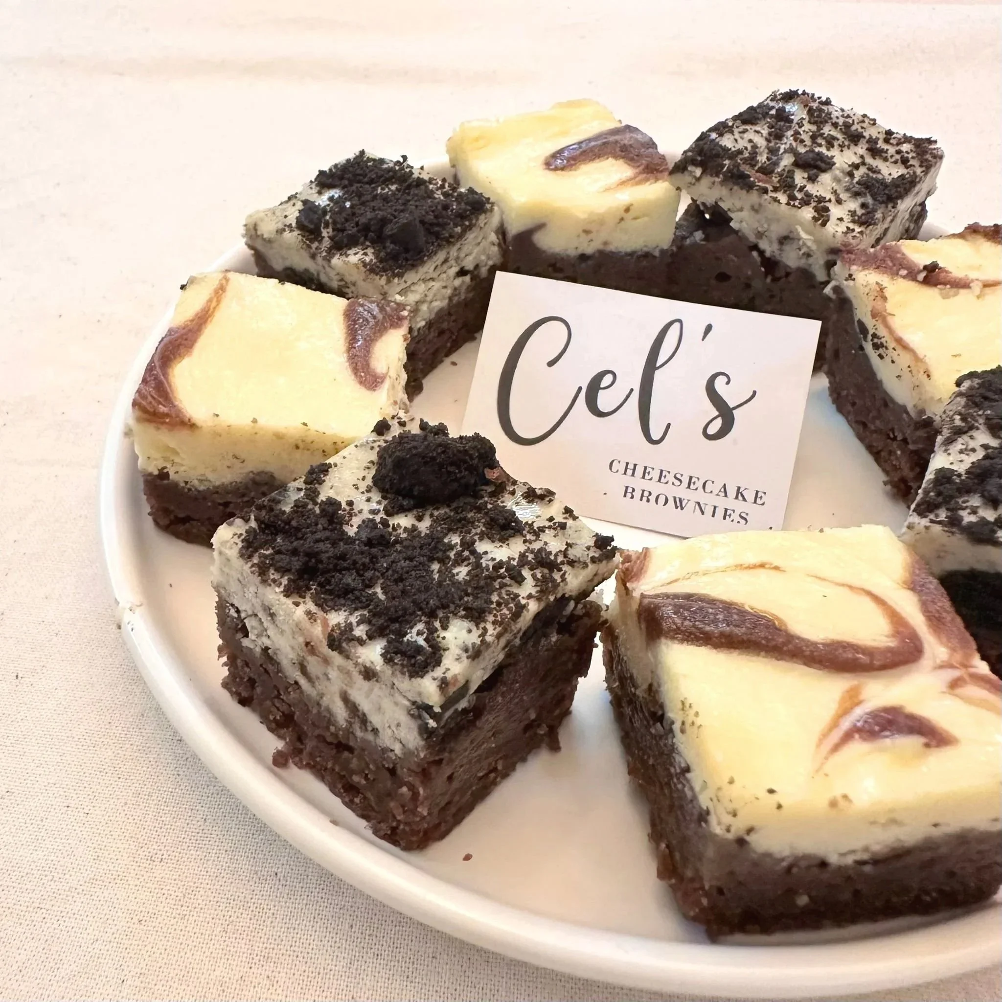 Assortment of cheesecake brownies  featuring the classic and Oreo flavours displayed on a white plate.