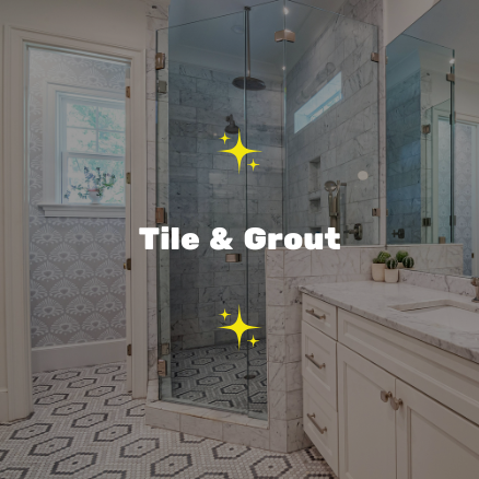 Bathroom with glass shower enclosure, tile and grout flooring, white vanity, and window with patterned wallpaper outside the shower.