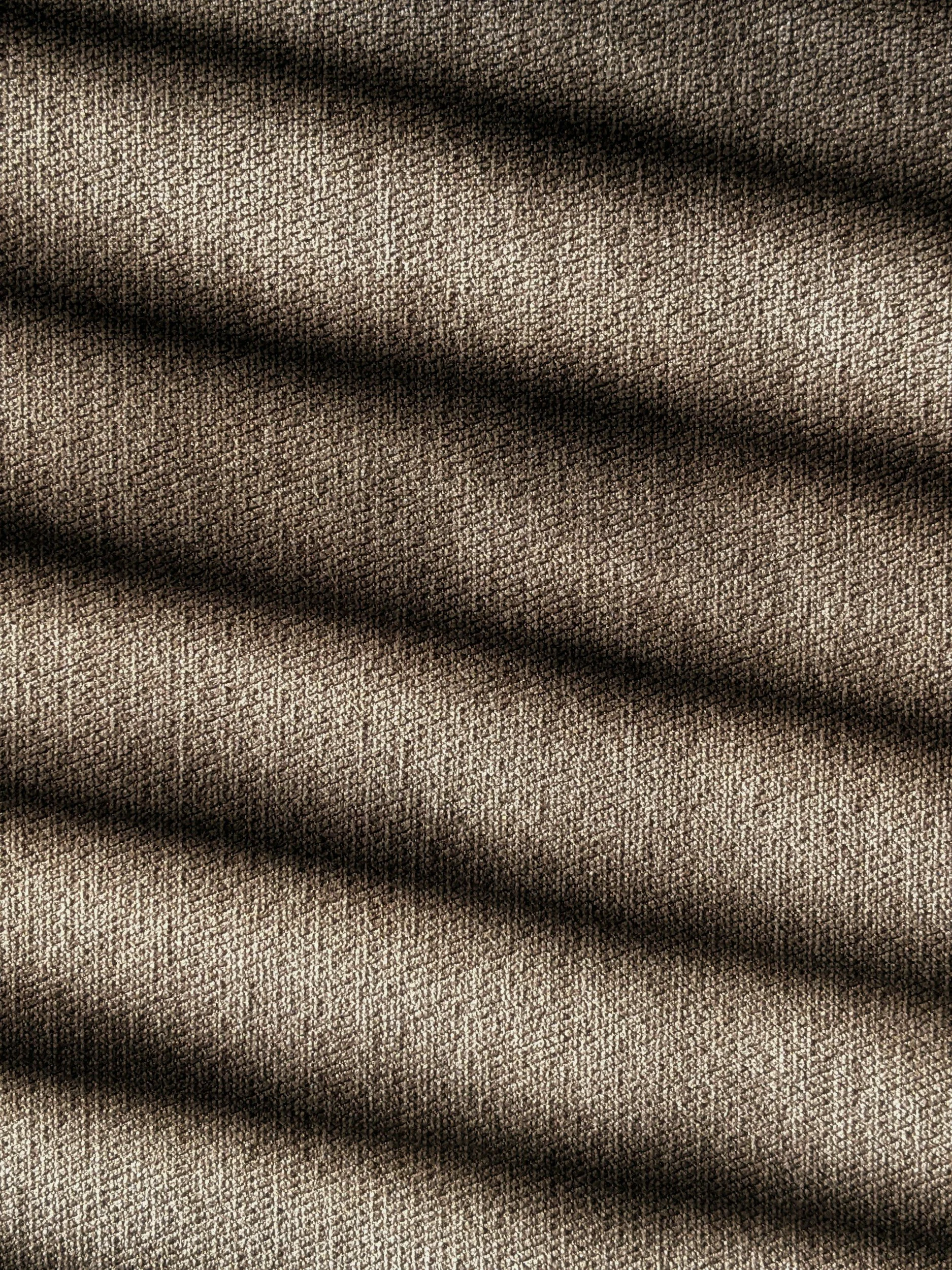 Close-up of textured brown fabric with black shadows cast across it.